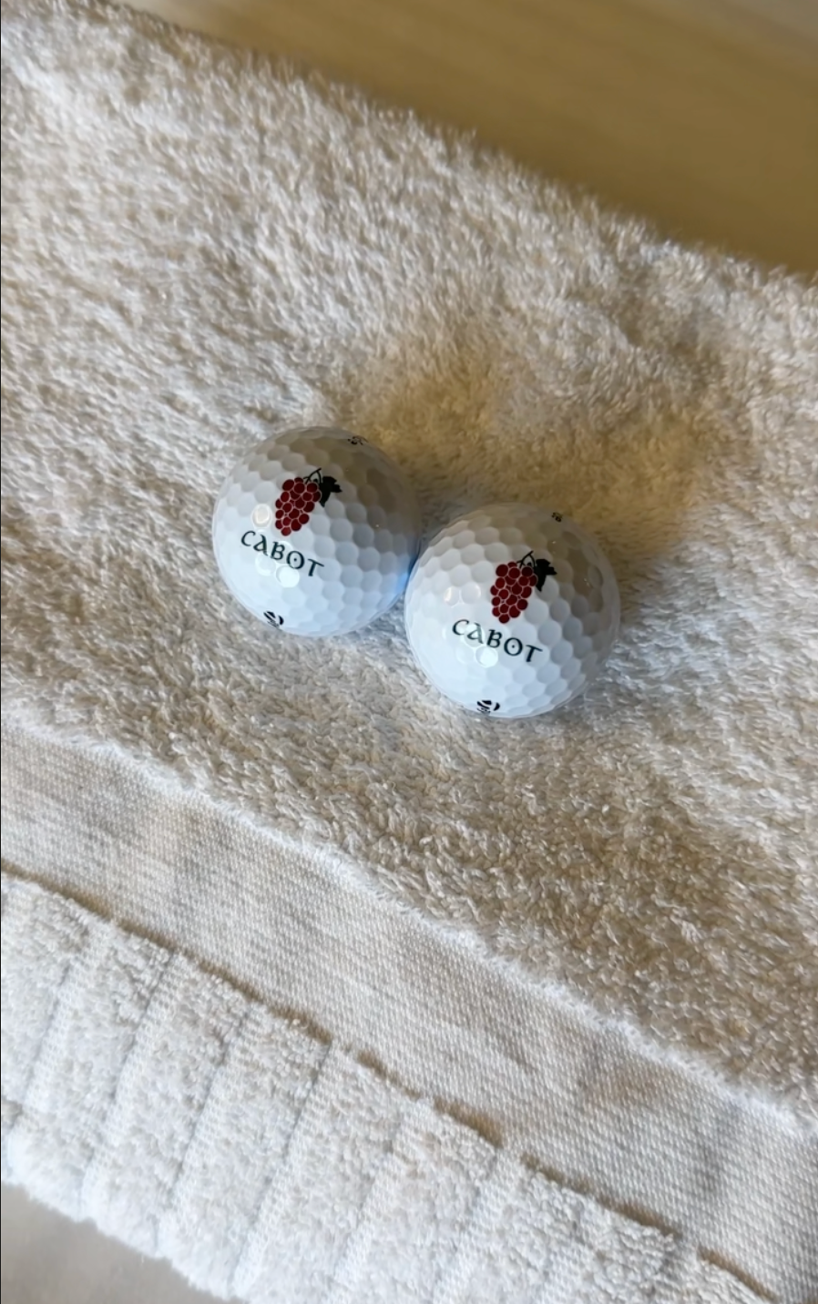 Two Cabot Bordeaux logo golf balls on a spa towel, the keepsake from the Birdie Massage